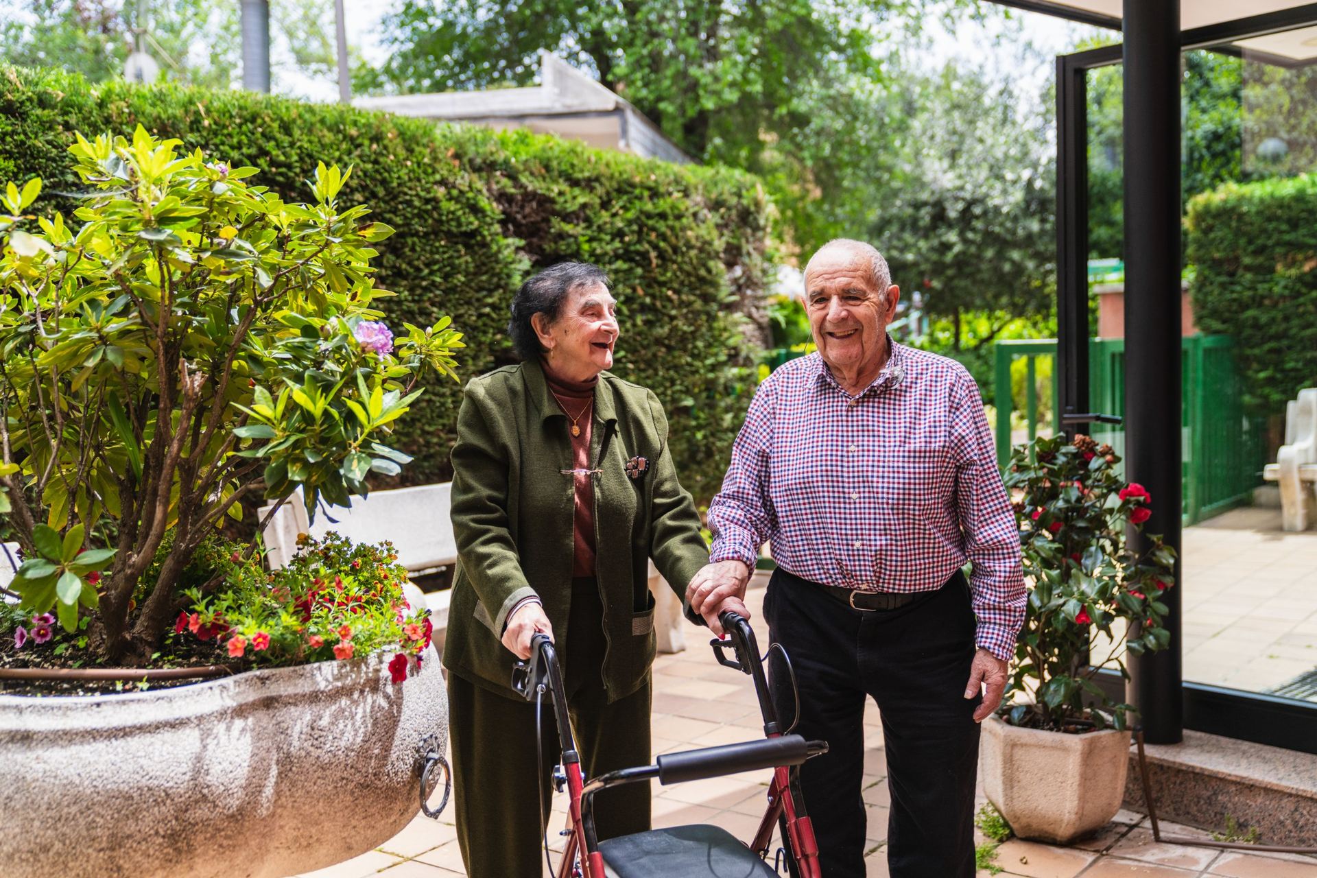 Casal de idosos caminhando com andador em um jardim